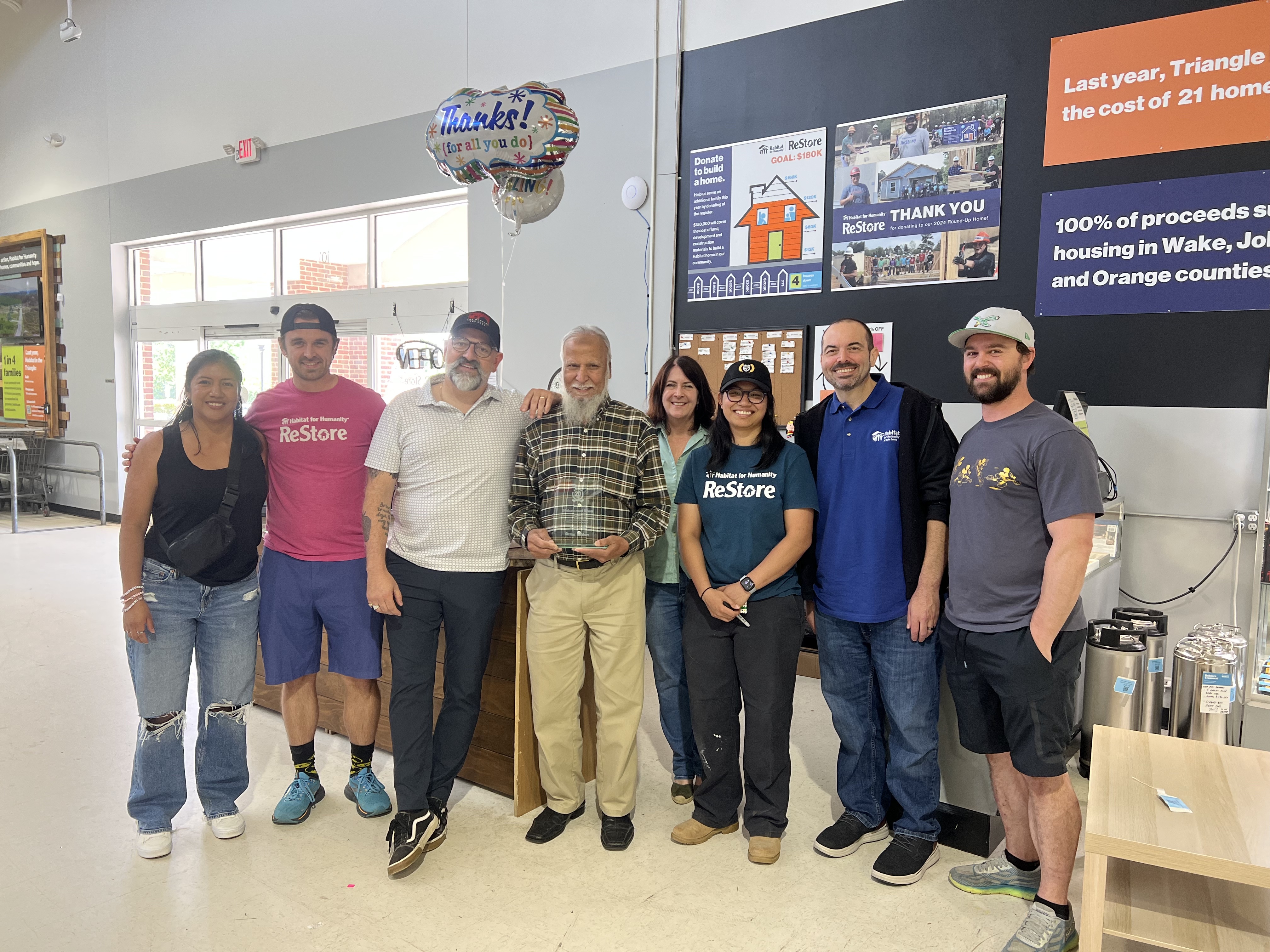 Mohammad Khan stands with Habitat staff after receiving anniversary plaque